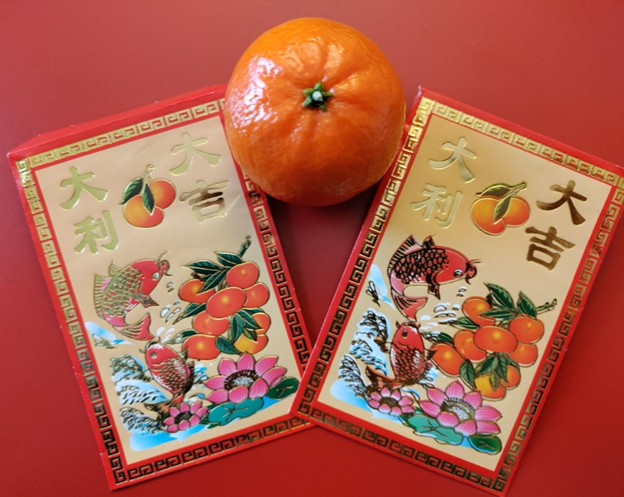 Photo of Chinese Red envelopes and citrus fruit for good luck in the Chinese New Year.