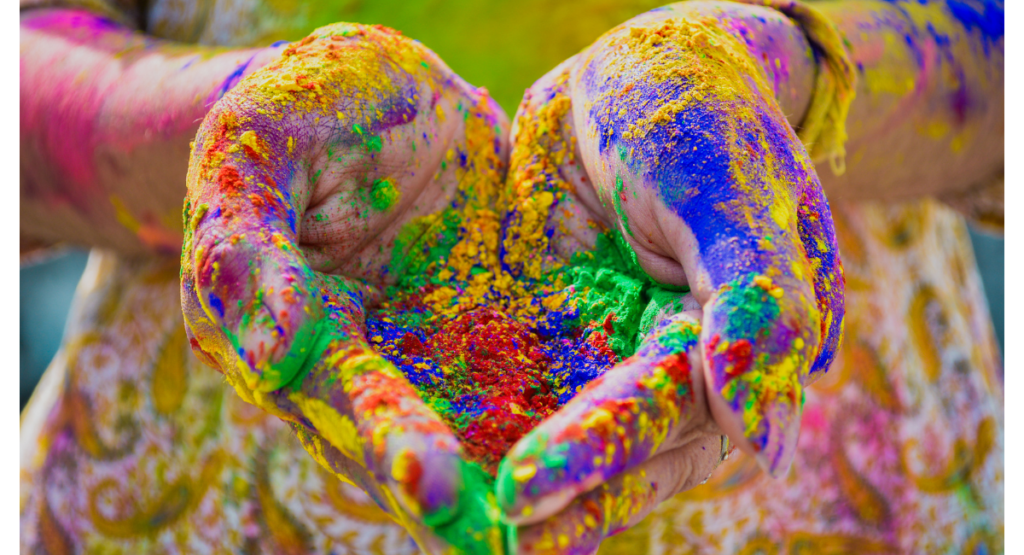 Image of 2 hands cupped together holding colored powder to celebrate Holi